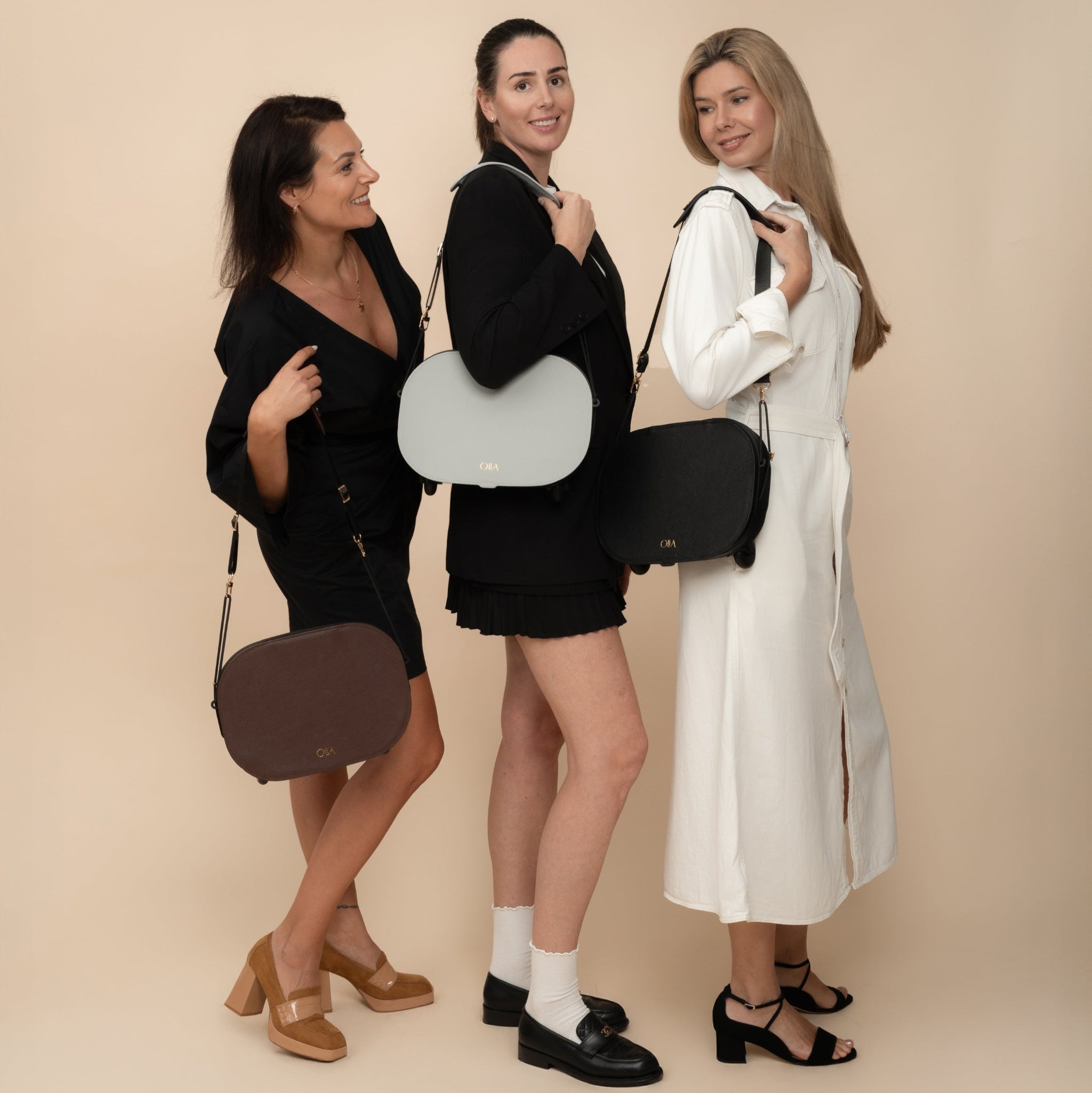Three female models showcasing Olla Bags in handbag configuration, featuring brown, gray, and black leather options