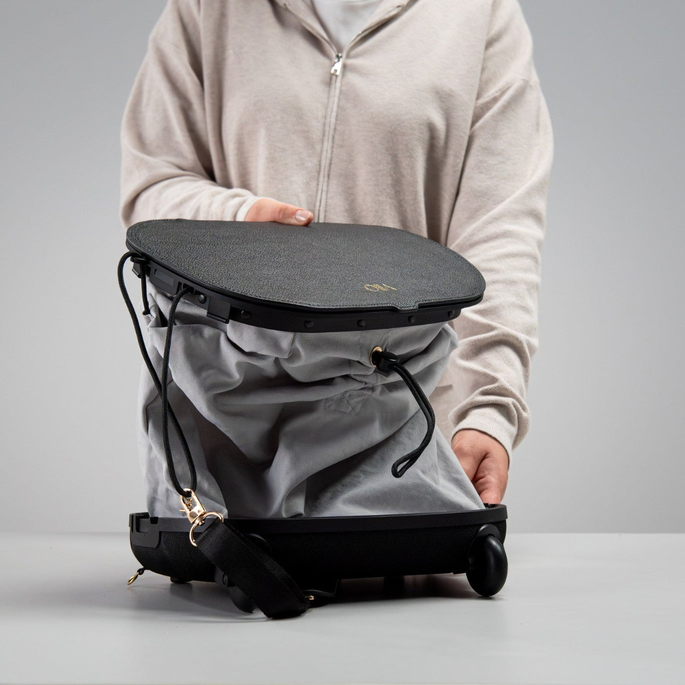 Person demonstrating Olla Bag partially expanded from handbag to trolley configuration, showing convertible feature