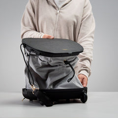 Person demonstrating Olla Bag partially expanded from handbag to trolley configuration, showing convertible feature