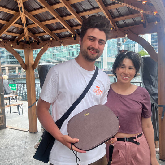 Two people standing under a wooden gazebo with a cityscape background