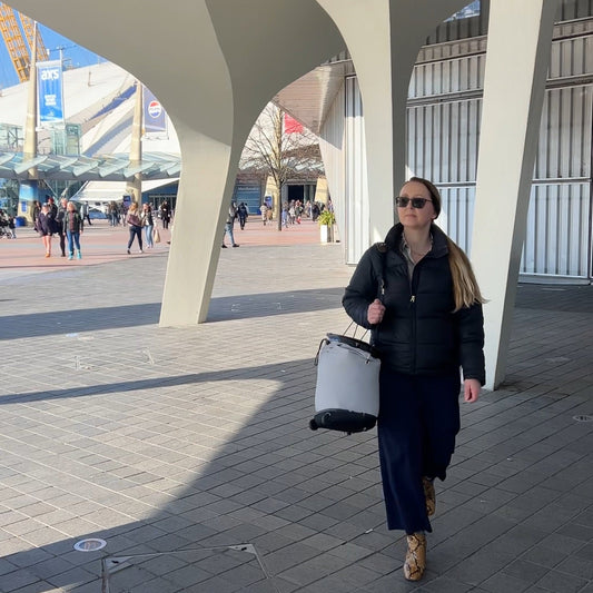 Person walking with a suitcase under a modern architectural structure